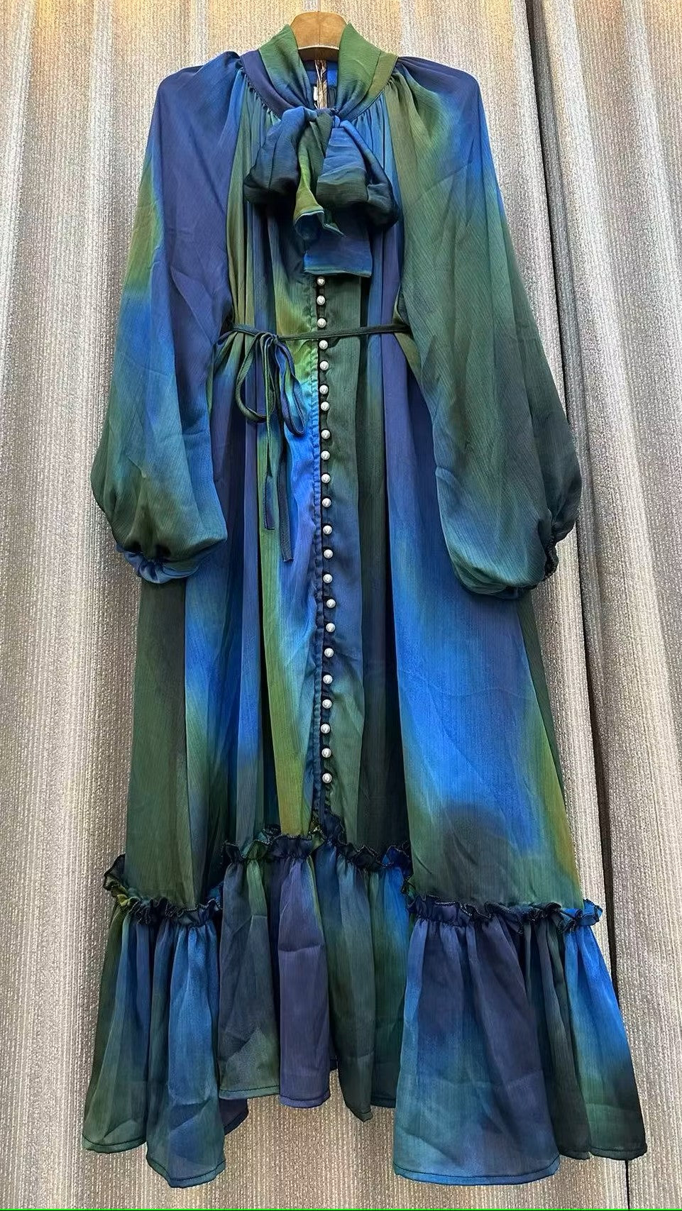 Blue/Green Color - Pleasing Patterns Dress - Midi Length - Long Lantern Sleeves with Elastic Cuffs - Ruffle on Bottom - Round Neckline with Tieable Bow at Neck - Detail Buttons on Front - Cinchable Tie on Waist